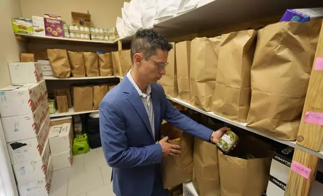Felipe Sousa Lazaballet, executive director of the Hope Community Center looks over inventory for disaster relief needs in the center's food pantry Thursday, Aug. 14, 2025, in Apopka, Fla. (AP Photo/John Raoux)