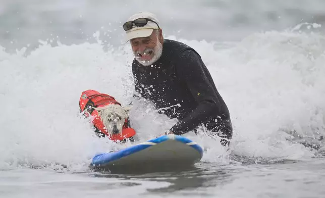 Don Horn helps Petey catch a wave during the World Dog Surfing Championships Saturday, Aug. 2, 2025, in Pacifica, Calif. (AP Photo/Eakin Howard)