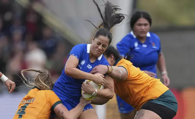 Fa'asua Makisi of Samoa, center, is tackled by Kaitlan Leaney of Australia, left, during the group A match at the 2025 Women's Rugby World Cup between Australia and Samoa in Manchester, England, Saturday, Aug. 23, 2025. (AP Photo/Dave Shopland)