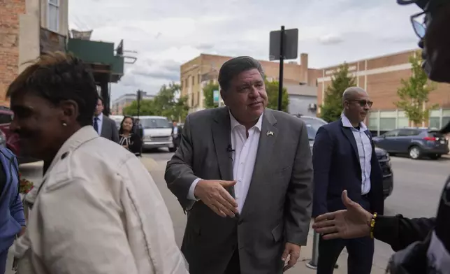 Illinois Gov. J.B. Pritzker greets people outside of Cleo's Southern Cuisine, Wednesday, Aug. 27, 2025, in the Bronzeville neighborhood of Chicago. (AP Photo/Erin Hooley)