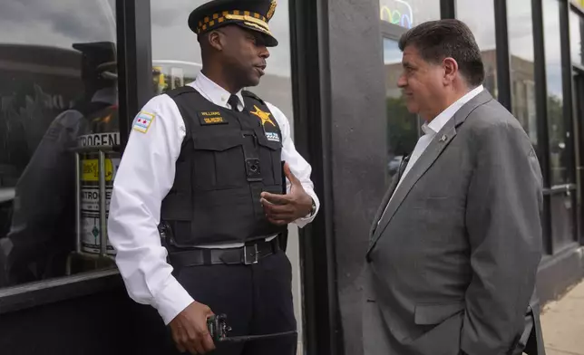 Chicago Police Cmdr, Herbert Williams, left, speaks with Illinois Gov. J.B. Pritzker Wednesday, Aug. 27, 2025, in the Bronzeville neighborhood of Chicago. (AP Photo/Erin Hooley)