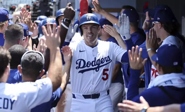 Los Angeles Dodgers' Freddie Freeman is congratulated in the dugout after hitting a three-run home run to score Shohei Ohtani and Mookie Betts against the San Diego Padres pitcher Yu Darvish during the first inning of a baseball game, Sunday, Aug. 17, 2025, in Los Angeles. (AP Photo/Kevork Djansezian)