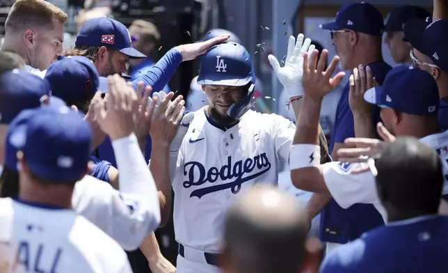 Los Angeles Dodgers outfielder Andy Pages is congratulated in the dugout after hitting a one-run home run against San Diego Padres pitcher Yu Darvish during the first inning of a baseball game, Sunday, Aug. 17, 2025, in Los Angeles. (AP Photo/Kevork Djansezian)