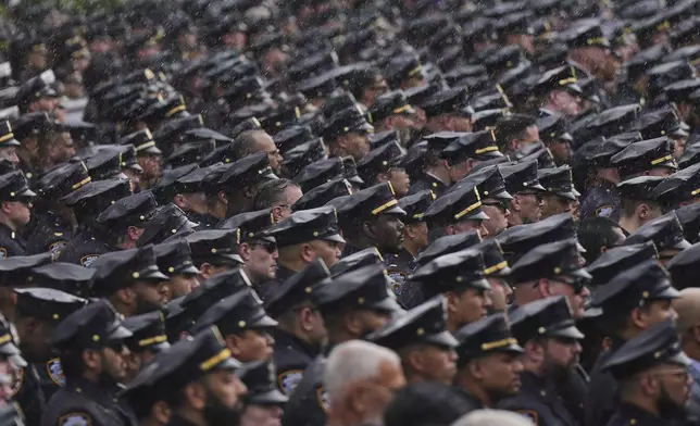 New York Police officers stand at attention as the hearse carrying the casket of officer Didarul Islam passes after his funeral, Thursday, July 31, 2025, in New York. (AP Photo/Angelina Katsanis)