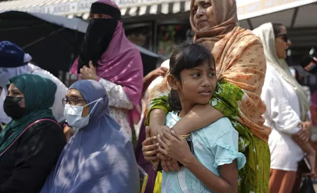 Women and children gather near the Parkchester Jame Masjid mosque before the funeral of officer Didarul Islam, Thursday, July 31, 2025, in New York. (AP Photo/Angelina Katsanis)