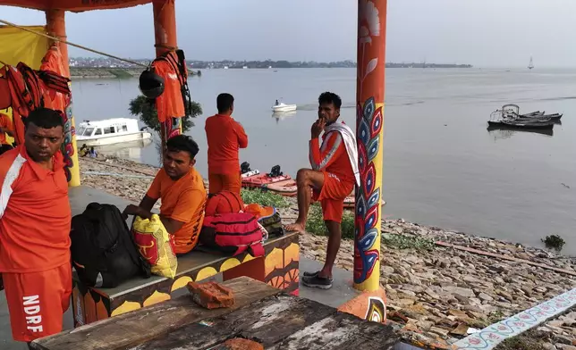 Members of India's National Disaster Response Force (NDRF) take a break during a rescue operation from the flooded residential areas along the banks of the river Ganga following heavy monsoon rains, in Prayagraj, India, Tuesday, Aug. 5, 2025. (AP Photo/Rajesh Kumar Singh)