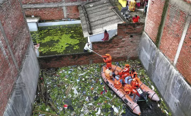 Members of India's National Disaster Response Force distribute food supplies to stranded residents in a submerged area following heavy monsoon rains along the banks of the River Ganga, in Prayagraj, India Tuesday, Aug. 5, 2025. (AP Photo/Rajesh Kumar Singh)