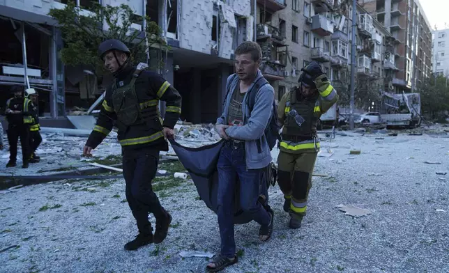 Rescue workers carry an injured woman after a Russian strike on residential neighbourhood in Kyiv, Ukraine, on Thursday, Aug. 28, 2025. (AP Photo/Evgeniy Maloletka)