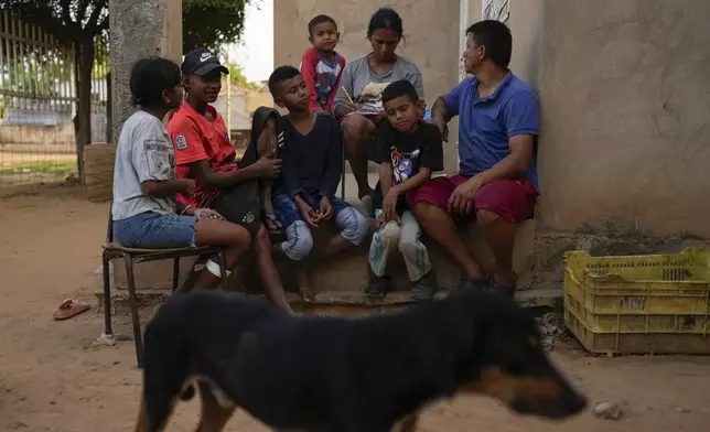 Jose Romero, right, his wife Yoselin Perez and their five children, who returned to Venezuela from Mexico after abandoning plans to reach the United States amid President Donald Trump's migration crackdown, sit on their porch in Maracaibo, Venezuela, Monday, June 16, 2025. (AP Photo/Matias Delacroix)