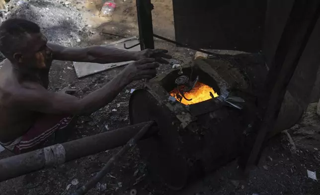 A worker hired by the Romero Perez family, who returned to Venezuela from Mexico after abandoning plans to reach the United States amid President Donald Trump's migration crackdown, melts aluminum to make pots in Maracaibo, Venezuela, Monday, June 16, 2025. (AP Photo/Matias Delacroix)