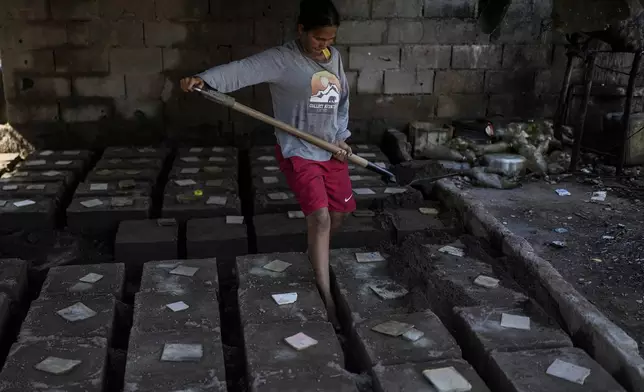 Yosbelin Perez, who returned to Venezuela from Mexico with her husband and five children after abandoning plans to reach the United States amid President Donald Trump's migration crackdown, covers molds with molten aluminum to make griddles, in Maracaibo, Venezuela, Monday, June 16, 2025. (AP Photo/Matias Delacroix)