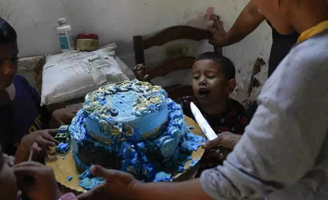 Jorman Romero, one of five children who returned to Venezuela from Mexico with their parents after abandoning plans to reach the United States amid President Donald Trump's migration crackdown, asks his mother Yosbelin Perez for a piece of cake, in Maracaibo, Venezuela, Monday, June 16, 2025.(AP Photo/Matias Delacroix)