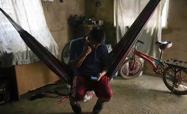 Jose Romero, who returned to Venezuela from Mexico with his wife and their five children after abandoning plans to reach the United States amid President Donald Trump's migration crackdown, looks at his phone, in Maracaibo, Venezuela, Monday, June 16, 2025. (AP Photo/Matias Delacroix)
