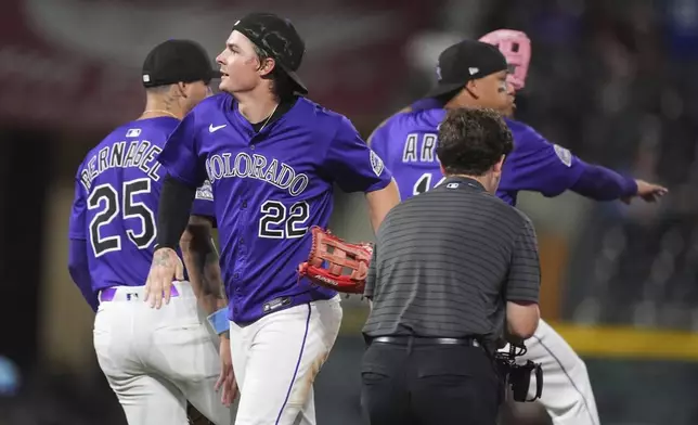 Colorado Rockies right fielder Mickey Moniak (22) celebrates with first baseman Warming Bernabel (25) and third baseman Orlando Arcia after defeating the Los Angeles Dodgers in a baseball game Wednesday, Aug. 20, 2025, in Denver. (AP Photo/David Zalubowski)