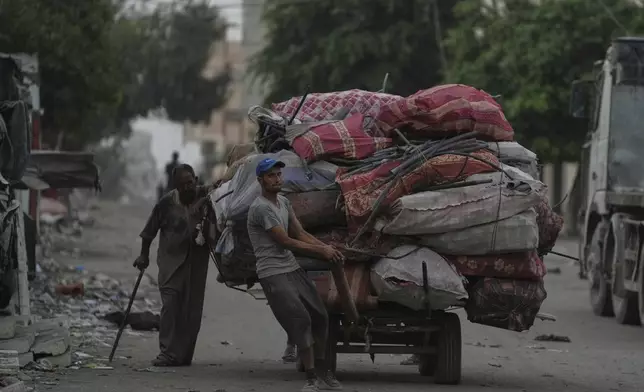 Displaced Palestinians fleeing Jabaliya move with their belongings on a street in Gaza City, Tuesday, Aug. 26, 2025. (AP Photo/Jehad Alshrafi)