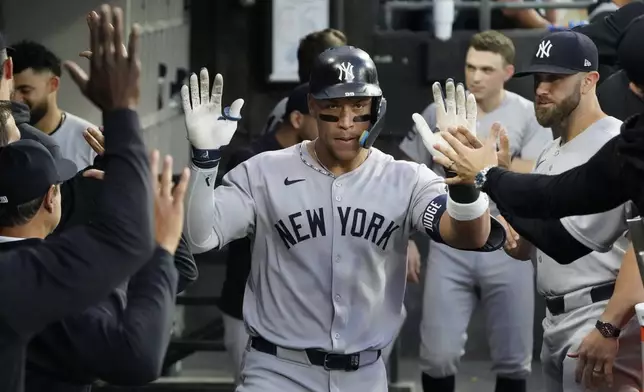 New York Yankees' Aaron Judge, right, is greeted in the dugout after hitting a home run against the Chicago White Sox during the fourth inning of a baseball game Saturday, Aug. 30, 2025, in Chicago. (AP Photo/David Banks)
