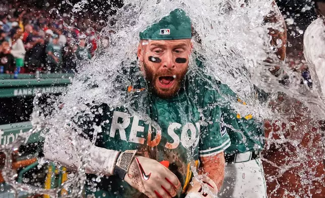 Boston Red Sox's Trevor Story is doused with ice water after his game-winning single in the bottom of the ninth inning of a baseball game against the Miami Marlins at Fenway Park, Friday, Aug. 15, 2025, in Boston. (AP Photo/Charles Krupa)