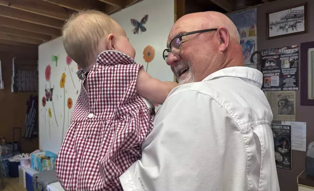 Mike Hardy holds his granddaughter inside his cabin at the Neshoba County Fair in Philadelphia, Miss., on Wednesday, July 30, 2025. (AP Photo/Sophie Bates)