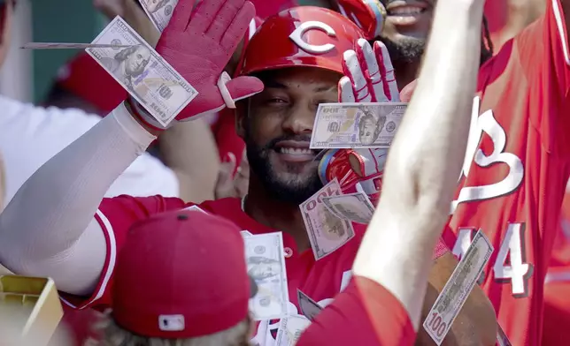 Teammates shower Cincinnati Reds' Miguel Andujar with play money in the dugout after his three-run home run during the third inning of a baseball game against the Pittsburgh Pirates, Sunday, Aug. 10, 2025, in Pittsburgh. (AP Photo/Matt Freed)