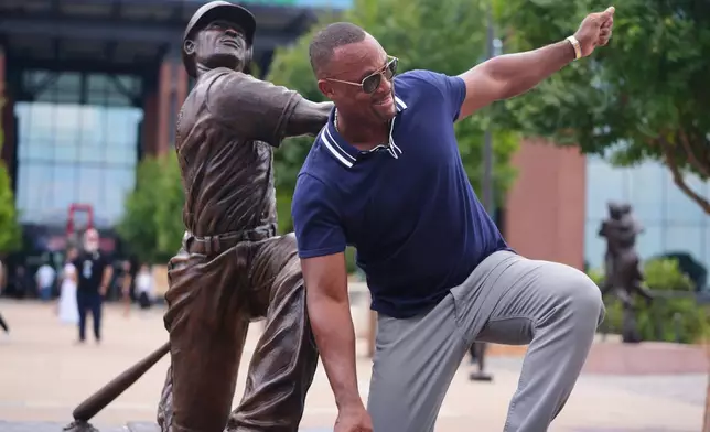 Former Texas Rangers player Adrian Beltre playfully tries to recreate the the pose for a statue of himself after it was unveiled before a baseball game between the Cleveland Guardians and the Rangers, Friday, Aug. 22, 2025, in Arlington, Texas. (AP Photo/LM Otero)