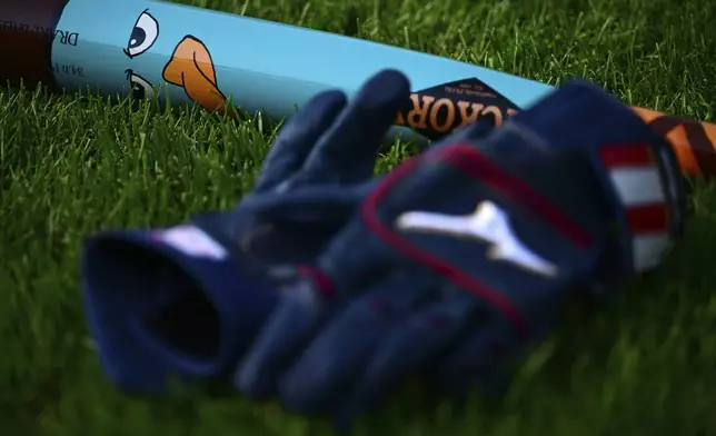 A custom bat for Players' Weekend lays in the grass before a game between the Atlanta Braves and Cleveland Guardians, Friday, Aug. 15, 2025, in Cleveland. (AP Photo/David Dermer)