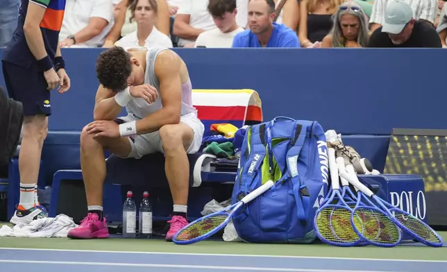 Ben Shelton, of the United States, reacts on the bench before retiring against Adrian Mannarino, of France, during the third round of the U.S. Open tennis championships, Friday, Aug. 29, 2025, in New York. (AP Photo/Kirsty Wigglesworth)