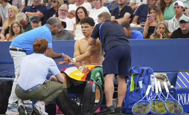 Trainers work on Ben Shelton, of the United States, during a break in play against Adrian Mannarino, of France, during the third round of the U.S. Open tennis championships, Friday, Aug. 29, 2025, in New York. (AP Photo/Kirsty Wigglesworth)