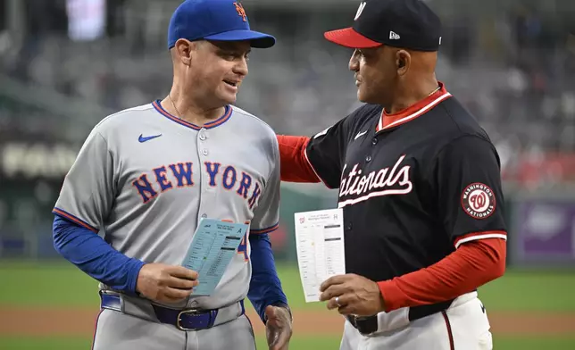 New York Mets manager Carlos Mendoza, and Washington Nationals interim manager Miguel Cairo meet at home plate to exchange lineup cards on Tuesday, Aug. 19, 2025, in Washington. They are the first Venezuelan born managers to face each other in a major league baseball game. (AP Photo/John McDonnell)
