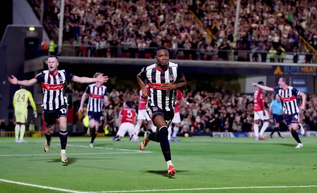 Grimsby Town's Tyrell Warren, center, celebrates scoring their side's second goal during an English League Cup second round soccer match against Manchester United, Wednesday, Aug. 27, 2025, at Hill Blundell Park in Grimsby, England. (Nigel French/PA via AP)