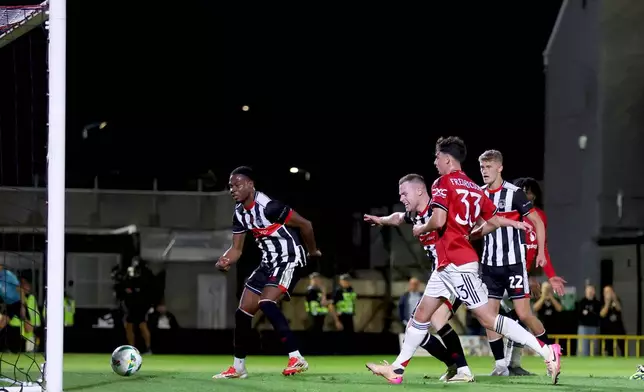 Grimsby Town's Tyrell Warren, left, scoring their side's second goal during an English League Cup second round soccer match against Manchester United, Wednesday, Aug. 27, 2025, at Hill Blundell Park in Grimsby, England. (Nigel French/PA via AP)