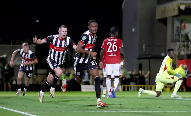 Grimsby Town's Tyrell Warren, center, celebrates scoring their side's second goal during an English League Cup second round soccer match against Manchester United, Wednesday, Aug. 27, 2025, at Hill Blundell Park in Grimsby, England. (Nigel French/PA via AP)