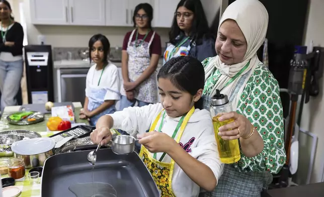 Shameem Syed helps student Zaaria Moosani during a cooking class at Olive Community Services, Tuesday, July 29, 2025, in Fullerton, Calif. (AP Photo/Zoë Meyers)