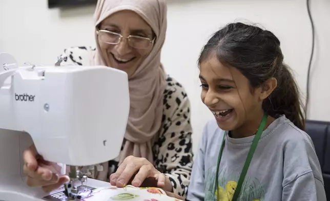 Amal Alalim helps a student in a sewing class at Olive Community Services, Tuesday, July 29, 2025, in Fullerton, Calif. The class was part of the organization's Intergenerational Summer Camp. (AP Photo/Zoë Meyers)