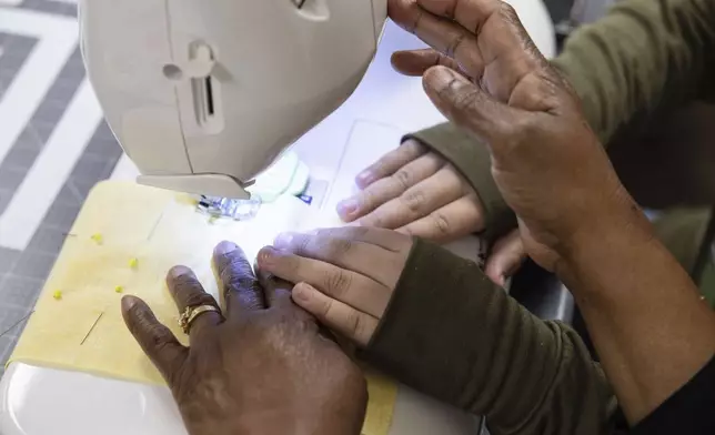 Yusra Jibali, 10, learns how to use a sewing machine with Farzana Khan at Olive Community Services, Tuesday, July 29, 2025, in Fullerton, Calif. (AP Photo/Zoë Meyers)