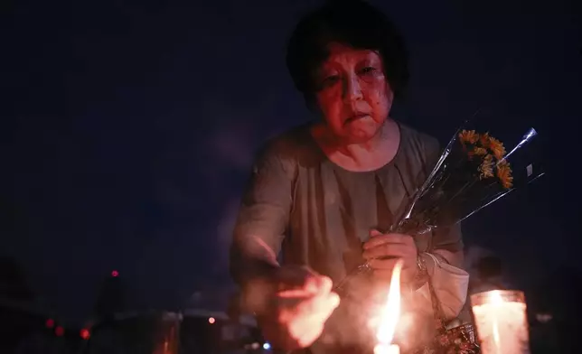 A visitor lights incense sticks at the Peace Memorial Park ahead of the memorial service to mark the 80th anniversary of the WWII U.S. atomic bombing in Hiroshima, Wednesday, Aug. 6, 2025, in Japan. (AP Photo/Louise Delmotte)