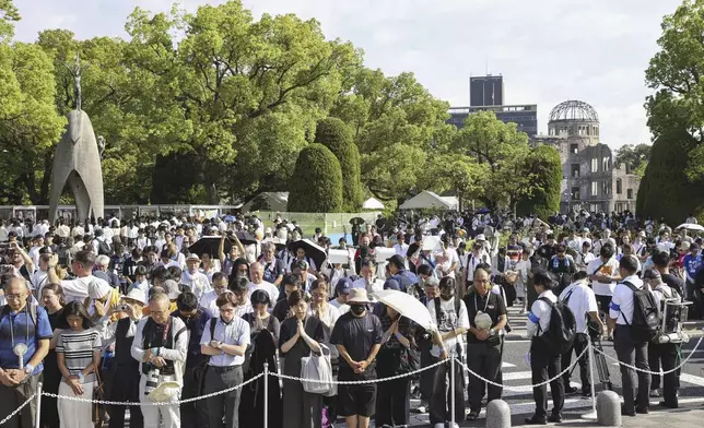 Visitors observe a minute of silence for the victims of the atomic bombing, at 8:15am, the time atomic bomb exploded over the city, at the Hiroshima Peace Memorial Park during the ceremony to mark the 80th anniversary of the bombing in Hiroshima, western Japan, Wednesday, Aug. 6, 2025. (Kyodo News via AP)