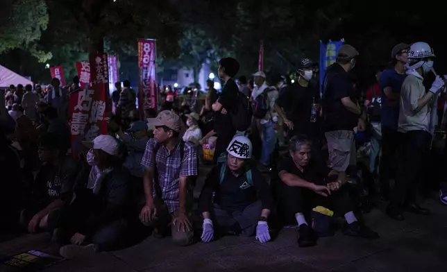 Protesters sit outside the Atomic Bomb Dome ahead of the memorial service to mark the 80th anniversary of the WWII U.S. atomic bombing in Hiroshima, Wednesday, Aug. 6, 2025, in Japan. (AP Photo/Louise Delmotte)