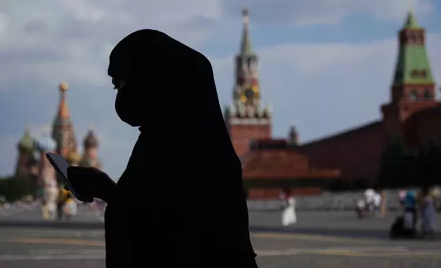 A woman wearing a niqab, checks her phone while walking along the Red Square in Moscow, Russia, Wednesday, July 30, 2025. (AP Photo/Pavel Bednyakov)