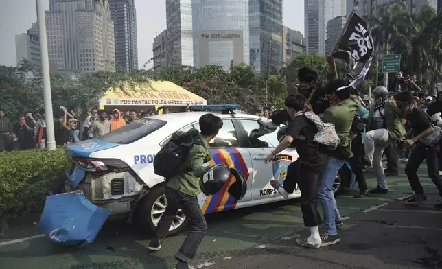 Students attack a police car during a protest following the death of a delivery rider who was run over by a police armored vehicle in a rally against lawmakers' privilege, in Jakarta, Indonesia, Friday, Aug. 29, 2025. (AP Photo/Tatan Syuflana)
