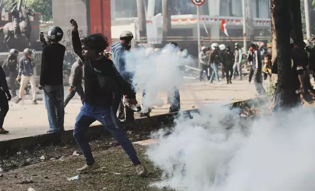 A man reacts as police fire tear gas during a protest following the death of a delivery rider who was run over by a police armored vehicle in a rally against lawmakers' privilege, in Jakarta, Indonesia, Friday, Aug. 29, 2025. (AP Photo/Achmad Ibrahim)
