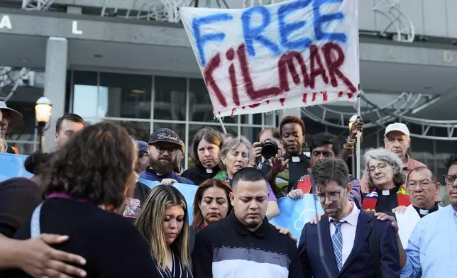 Jennifer Vasquez Sura, front left, her husband Kilmar Abrego Garcia, front center, and Attorney Simon Sandoval-Moshenberg, front right, attend a protest rally at the Immigration and Customs Enforcement field office in Baltimore, Monday, Aug. 25, 2025, to support Kilmar Abrego Garcia. (AP Photo/Stephanie Scarbrough)