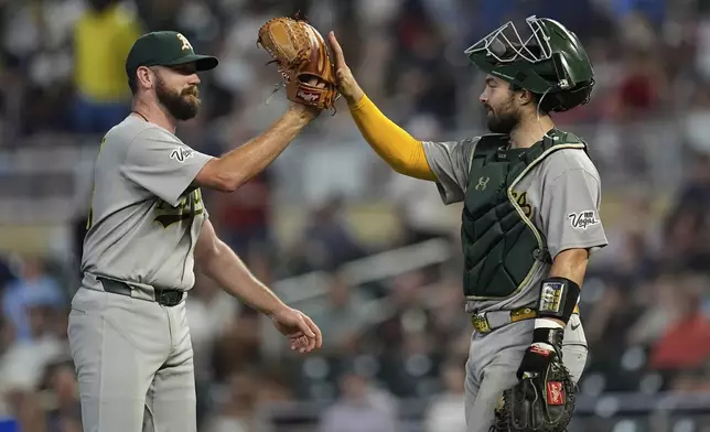 Athletics relief pitcher Hogan Harris (36), left, and catcher Shea Langeliers (23) celebrate after a baseball game against the Minnesota Twins Tuesday, Aug. 19, 2025, in Minneapolis. (AP Photo/Abbie Parr)