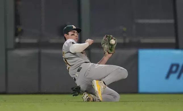 Athletics left fielder Tyler Soderstrom (21) slides to catch a line out hit by Minnesota Twins' Austin Martin (16) for the final out of a baseball game Tuesday, Aug. 19, 2025, in Minneapolis. (AP Photo/Abbie Parr)