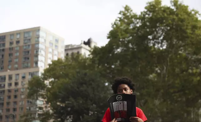 Jayon Rivera, 11, of Buffalo, N.Y., holds up a sign prior to the start of the March on Wall Street, Thursday, Aug. 28, 2025, in New York. (AP Photo/Heather Khalifa)