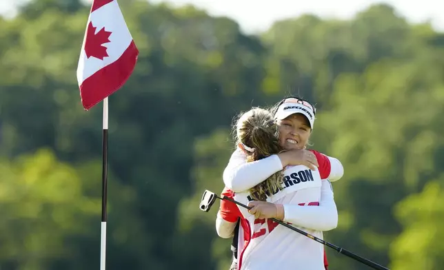 Brooke Henderson, right, of Canada, hugs her caddie, and sister, Brittany Henderson, left, after winning the Canadian Women's Open golf tourrnament on the 18th hole in Mississauga, Ontario, Sunday Aug. 24, 2025. (Frank Gunn/The Canadian Press via AP)