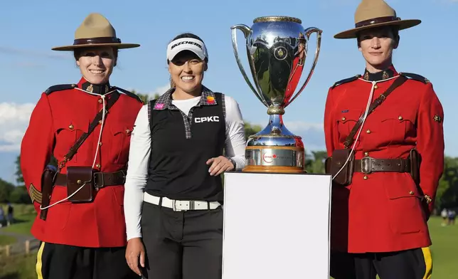 Brooke Henderson, of Canada, poses with the CPKC Championship Trophy alongside Royal Canadian Mounted Police officers after winning the Canadian Women's Open at Mississauga Golf and Country Club in Mississauga, Ontario, on Sunday, August 24, 2025. (Frank Gunn/The Canadian Press via AP)