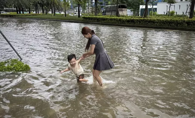 A mother and her son play in the flood in the aftermath of Typhoon Kajiki in Hanoi, Vietnam, Wednesday, Aug. 27, 2025. (AP Photo/Hau Dinh)