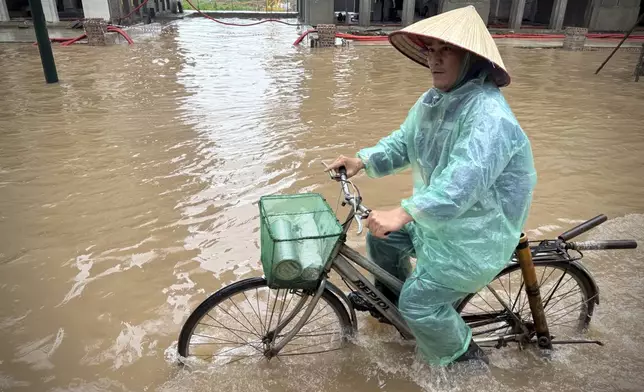 A man rides a bicycle on a flooded street caused by Typhoon Kajiki in Hanoi, Vietnam, Wednesday, Aug. 27, 2025. (AP Photo/Hau Dinh)