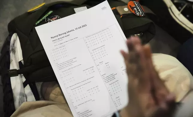 A participant reads her music notation sheet for "You'll Be In My Heart" by Phil Collins, during a gathering of "Nyanyi Bareng Jakarta" or "Singing Together Jakarta" community in Jakarta, Indonesia, Saturday, July 19, 2025. (AP Photo/Dita Alangkara)