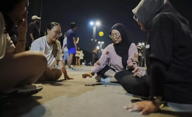 People play knucklebones ball during a community playing gathering in Jakarta, Indonesia, Friday, July 11, 2025. (AP Photo/Dita Alangkara)
